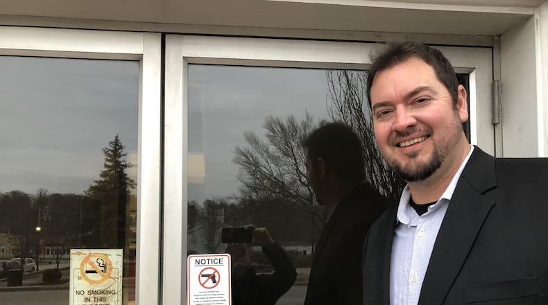 Lebanon City Councilman Joe Shafer points at one of the signs prohibiting the carrying of a firearm into city hall. Shafer and other council members have directed the law director to draft legislation to permit them to conceal-carry during meetings. STAFF/LAWRENCE BUDD