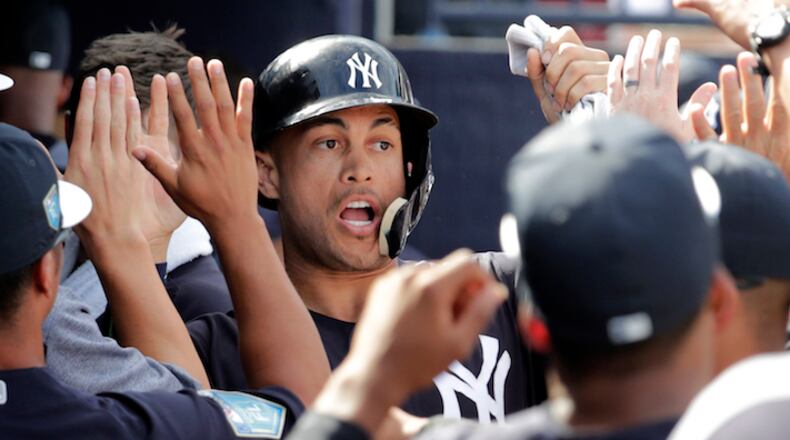 New York Yankees' Giancarlo Stanton is congratulated in the dugout after scoring on an RBI single by Didi Gregorius during the fifth inning of a baseball spring exhibition game against the Atlanta Braves, Friday, March 2, 2018, in Tampa, Fla. (AP Photo/Lynne Sladky)