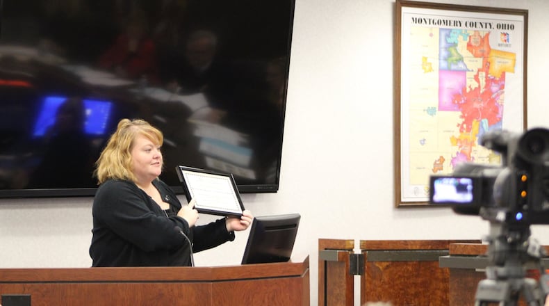 Sarah Fields, assistant director of the Montgomery County Child Support Enforcement Agency, holds up an award the organization received for having the largest improvement in its child support collection rate. Fields discussed the recognition at a recent county commission meeting. CORNELUS FROLIK / STAFF