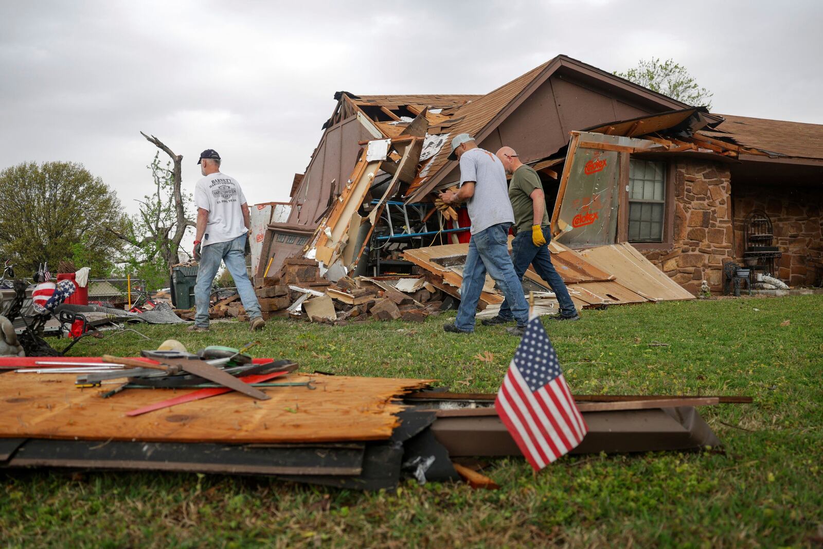Gary Deripaska, left, cleans up storm damage at his home off 96th Street North just west of Garnett Road, Wednesday, April 2, 2025, in Owasso, Okla. (Mike Simons/Tulsa World via AP)