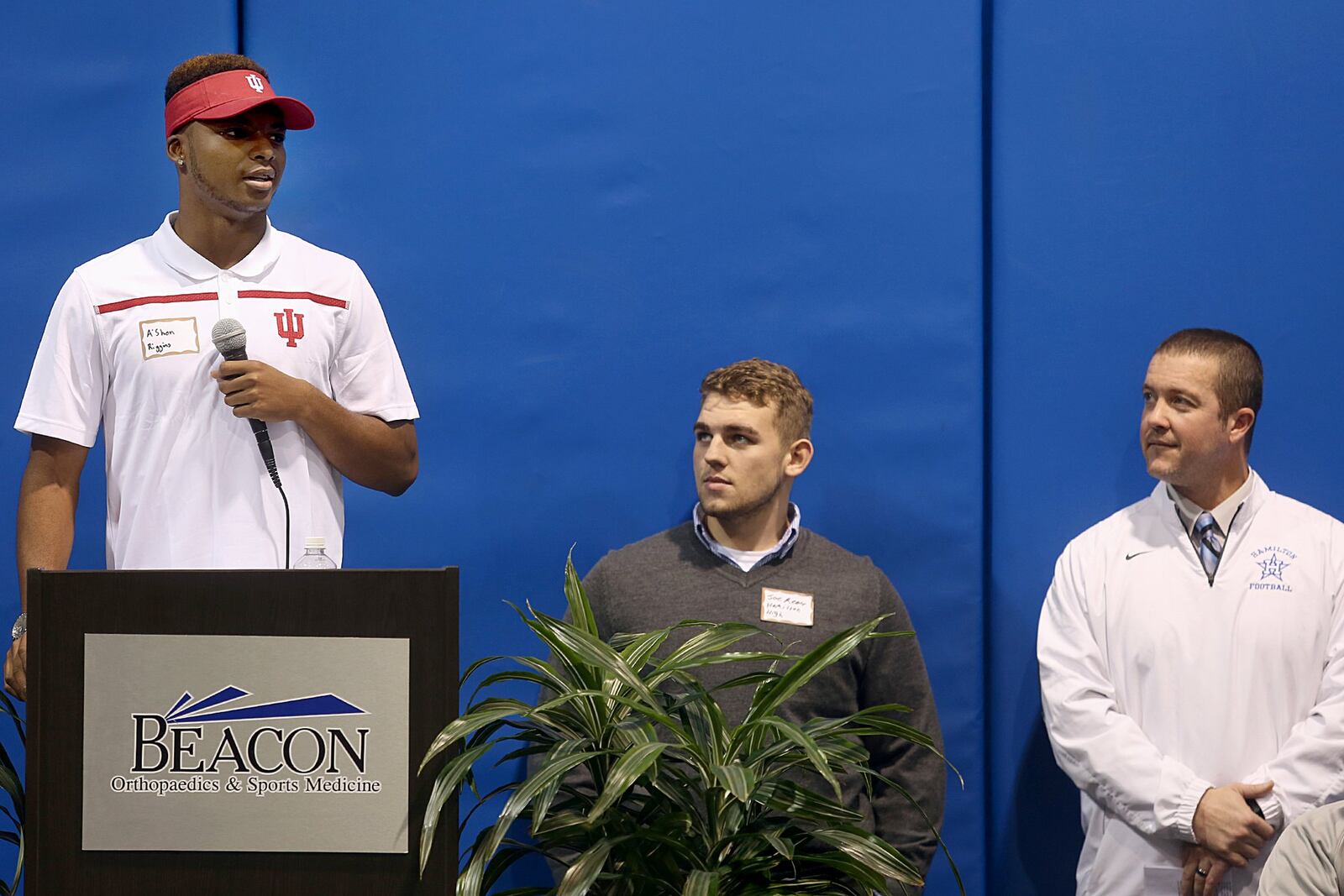 Hamilton’s A’Shon Riggins speaks as teammate Joey Reece and Big Blue coach Chad Murphy listen during the Greater Miami Conference’s National Signing Day event Wednesday at Beacon Orthopaedics Summit Woods in Sharonville. CONTRIBUTED PHOTO BY E.L. HUBBARD