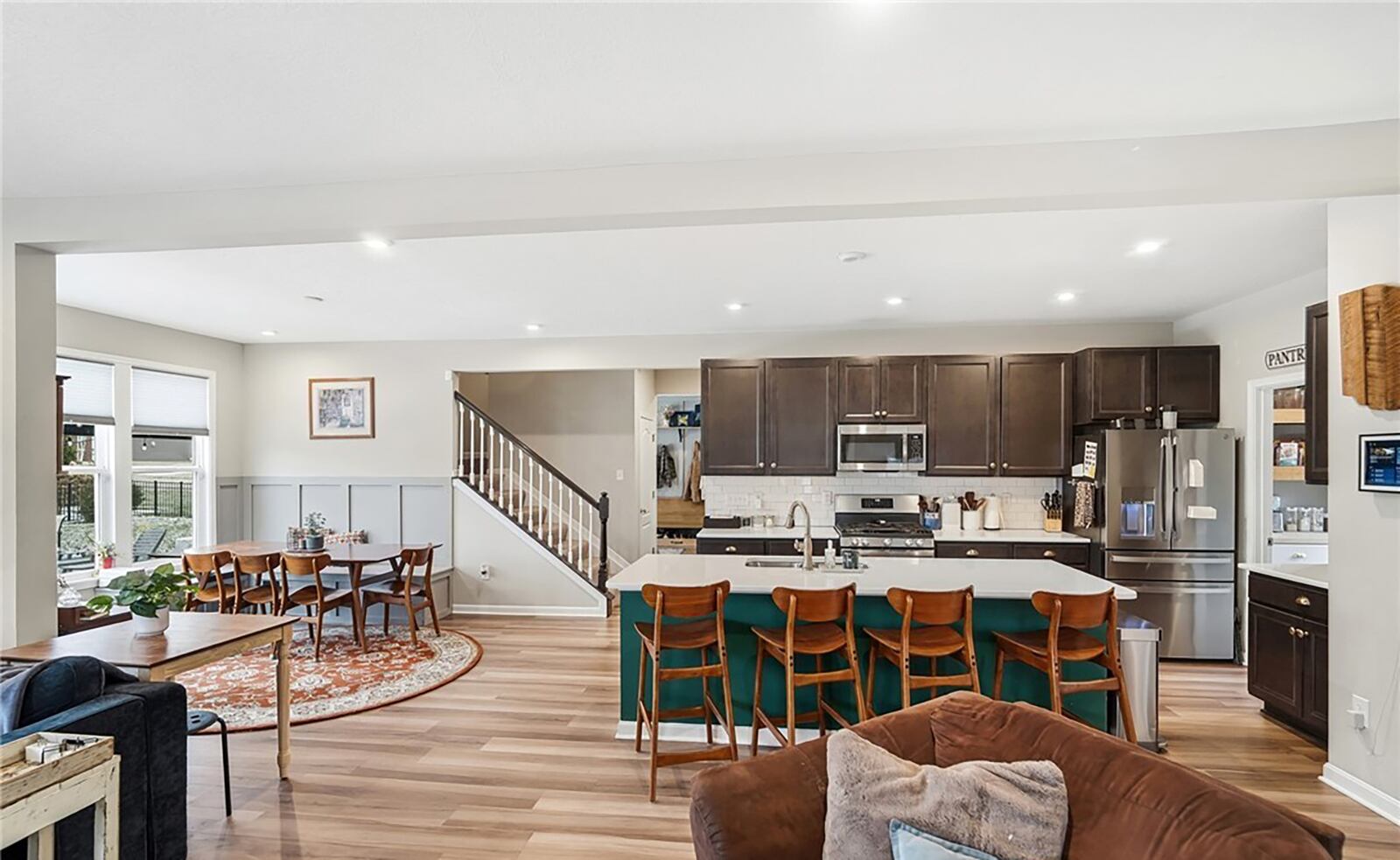 The open concept kitchen, dining and living rooms all have hardwood plank floors and recessed lighting. The kitchen has an island with bar seating and stainless appliances, and the family room has an electric fireplace. CONTRIBUTED