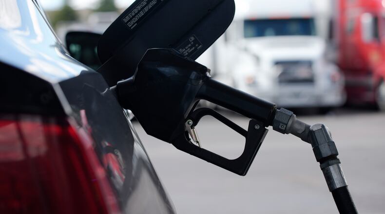 A pump handle hangs from a car at a gas station as motorists take to the road to start the Memorial Day weekend, Thursday, May 27, 2021, near Cheyenne, Wyo. (AP Photo/David Zalubowski)