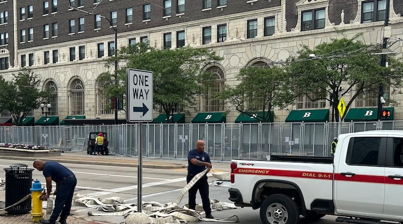 The green awnings of the Biltmore Towers building are partially hidden behind 8-foot metal fencing Wednesday as fire and security crews prepare downtown Dayton for the NATO Parliamentary Assembly. Jeremy P. Kelley / Staff