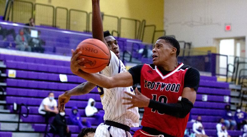 Trotwood-Madison's Anthony McComb drives on Thurgood Marshall's Markece Young during Saturday's season opener for both teams at Marshall. McComb scored a game-high 20 against his old team in a 102-56 victory. Jeff Gilbert/CONTRIBUTED