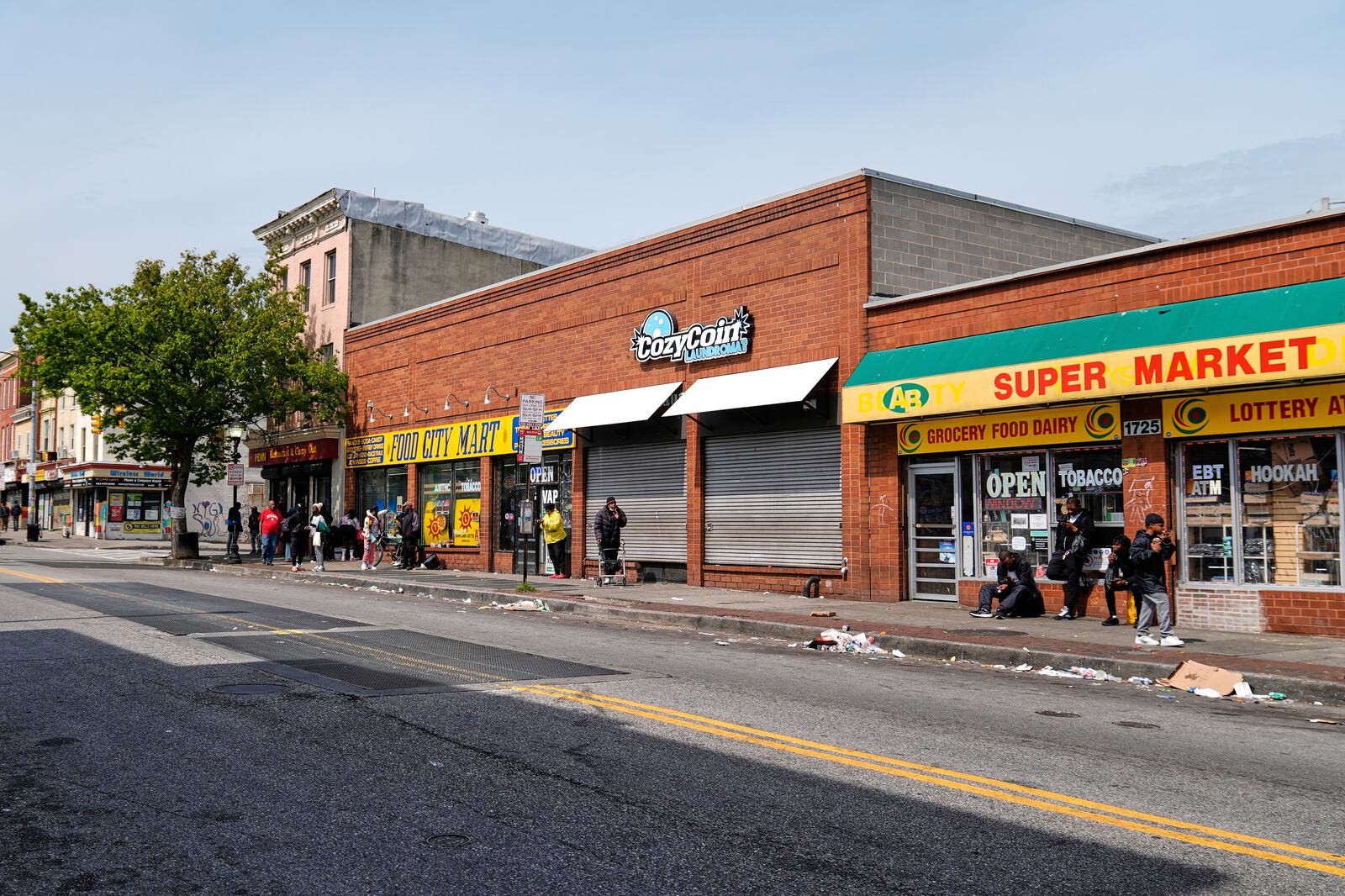 Litter lines the street as people walk and congregate on Pennsylvania Avenue near the Sandtown-Winchester neighborhood in Baltimore, Monday, April 14, 2025. (AP Photo/Stephanie Scarbrough)