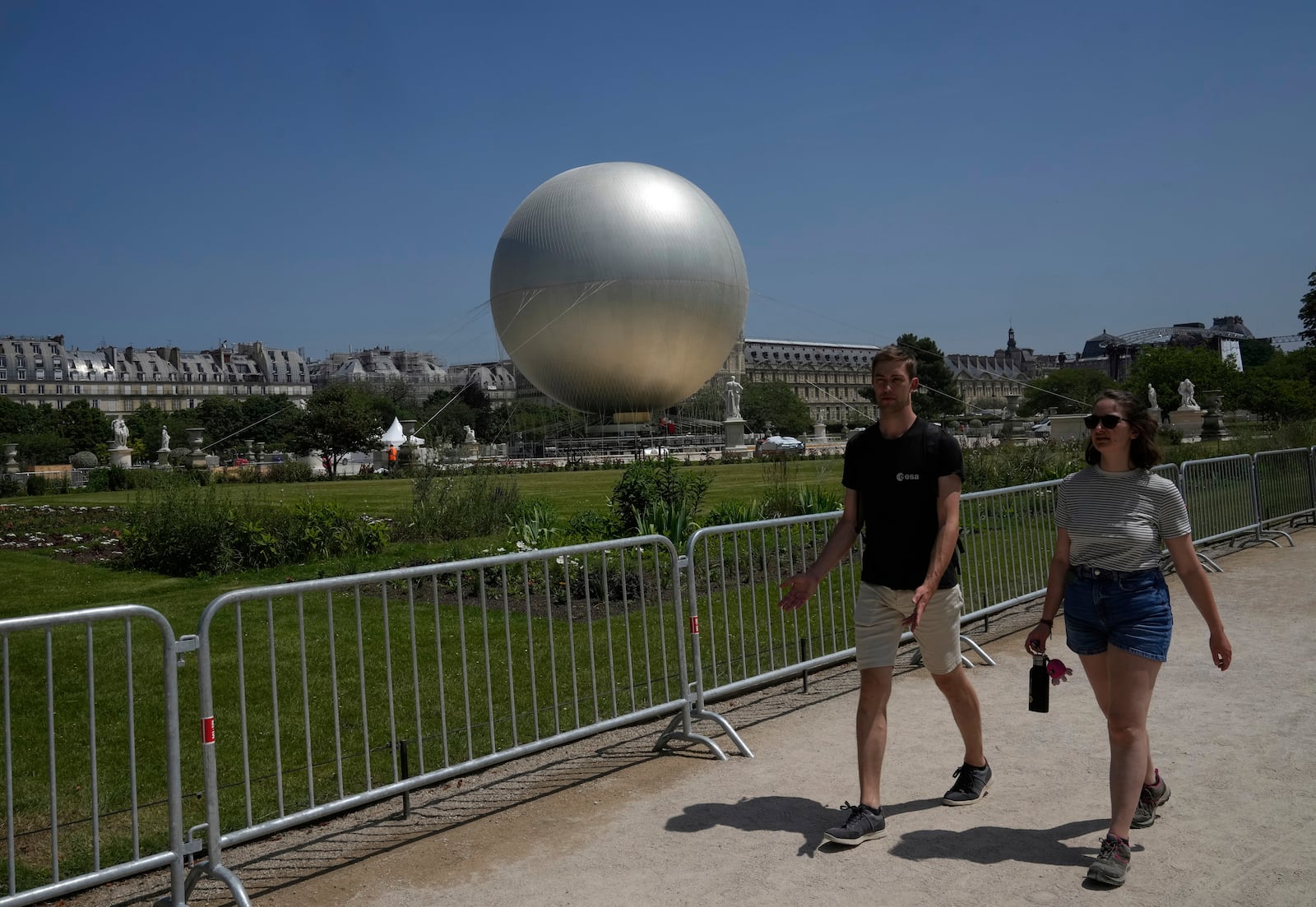 People walk past the Olympic cauldron at the Tuileries Gardens, ahead of its nightly summer relaunch starting June 21, in Paris, Thursday, June 12, 2025. (AP Photo/Michel Euler)