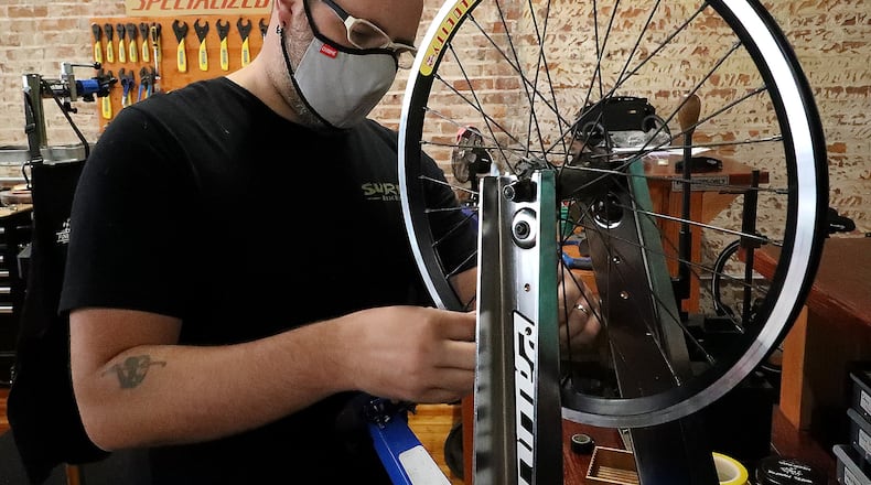 Jon Francis, the owner of Cyclotherapy, working on a clients bicycle wheel Thursday. BILL LACKEY/STAFF