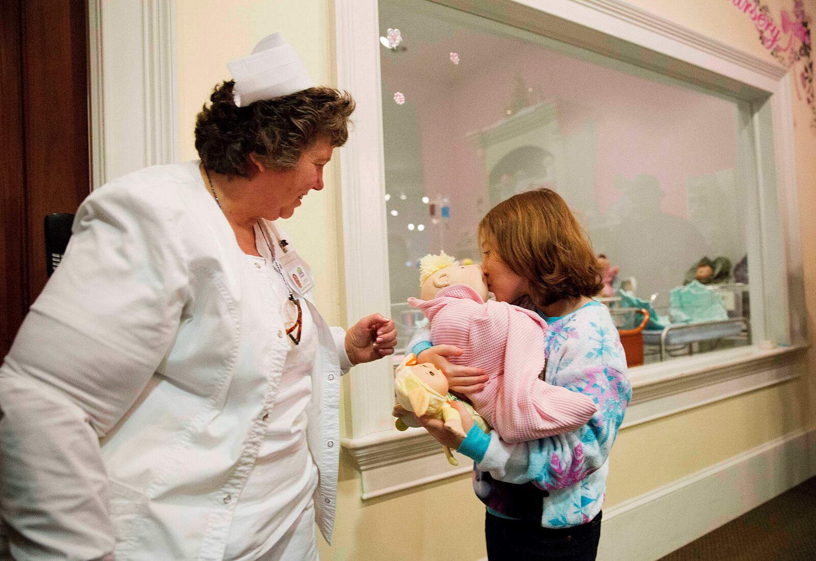 FILE - Talon Shaffer, right, kisses a Cabbage Patch Kid after it was delivered by Cyndi Pappadouplos, a "licensed patch nurse" at Babyland General Hospital, the birthplace of Cabbage Patch Kids, in Cleveland, Ga., on Nov. 21, 2014. (AP Photo/David Goldman, File)