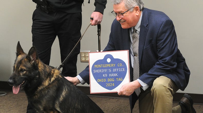 Montgomery County Auditor Karl Keith pets Montgomery County Sheriff's K9 Hank, after presenting his handler a undercover deputy his Ohio dog tag Thursday, Jan. 18, 2024. MARSHALL GORBY\STAFF
