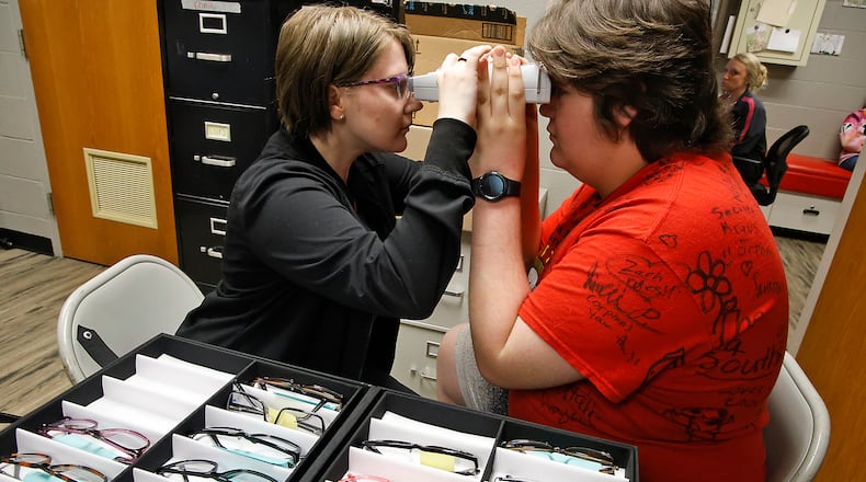 Southeastern Zachary Dennen gets fitted for a new pair of glasses by Devon Hutchins, a member of Optometrist Dr. Lindsay Florkey's staff, at Miami View School Friday, April 12, 2024. The Ohio Optometric Association held an In-School Eye Exam (iSEE) event at Miami View School. The iSEE program is operated by the Ohio Optometric Foundation (OOF) and provides comprehensive eye exams to students identified by school nurses as needing vision care. The students then get to pick out and are fitted for glasses that they receive at no charge. BILL LACKEY/STAFF