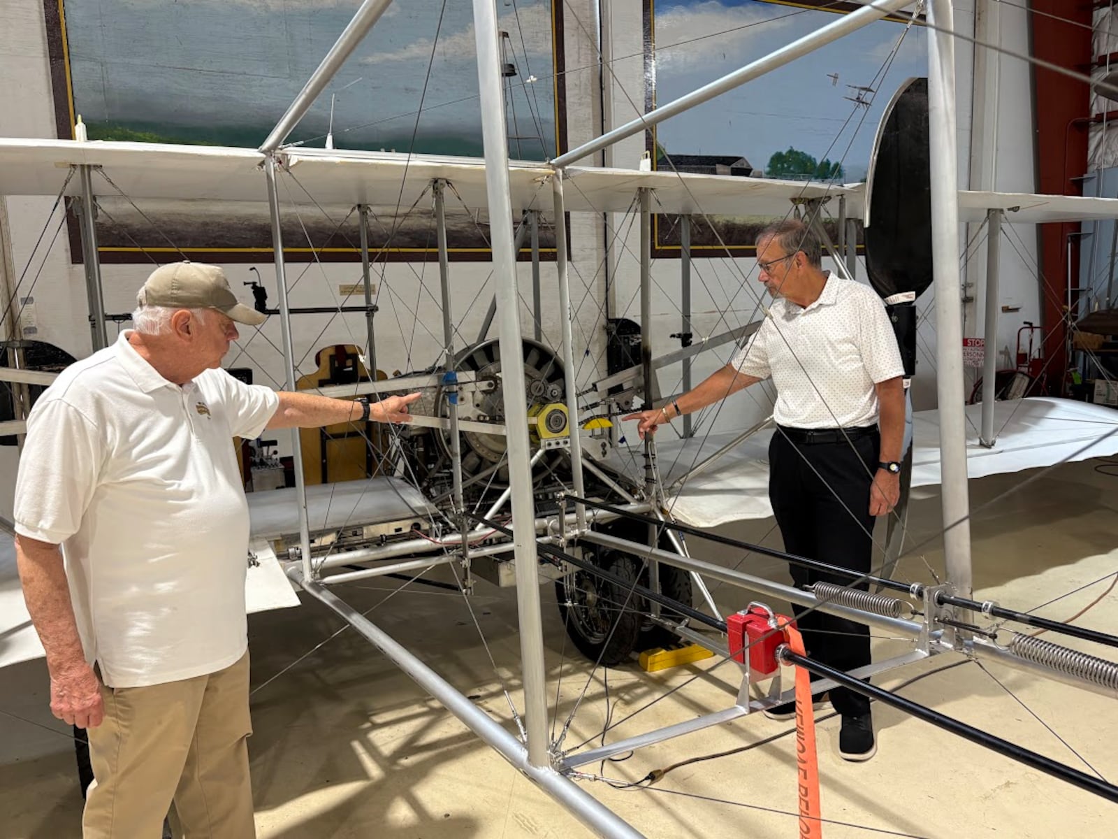 Jim Papa, left, chairman of the Wright "B" Flyer Inc. board of trustees, with Don Adams, the organization's president, point to the drive chains of a "lookalike" of the Wright Model B bi-plane at the Wright B Flyer Museum in Miami Twp. THOMAS GNAU/STAFF