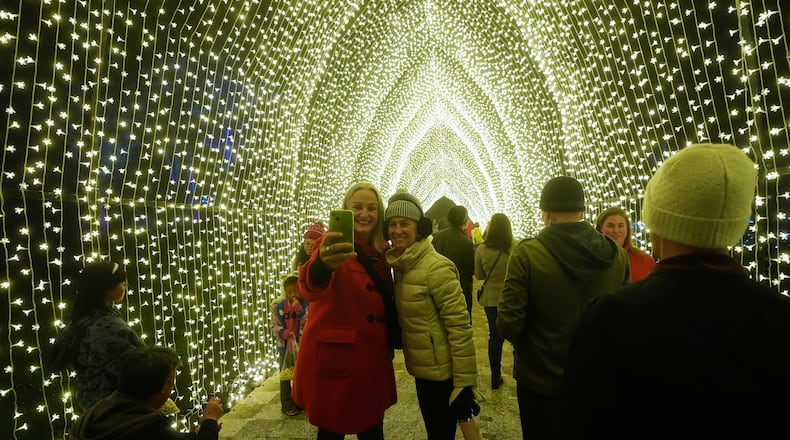 People take photos while walking through the San Francisco Botanical Garden's Winter Cathedral exhibit for Lightscape at Golden Gate Park in San Francisco, Wednesday, Dec. 17, 2025. (AP Photo/Jeff Chiu)