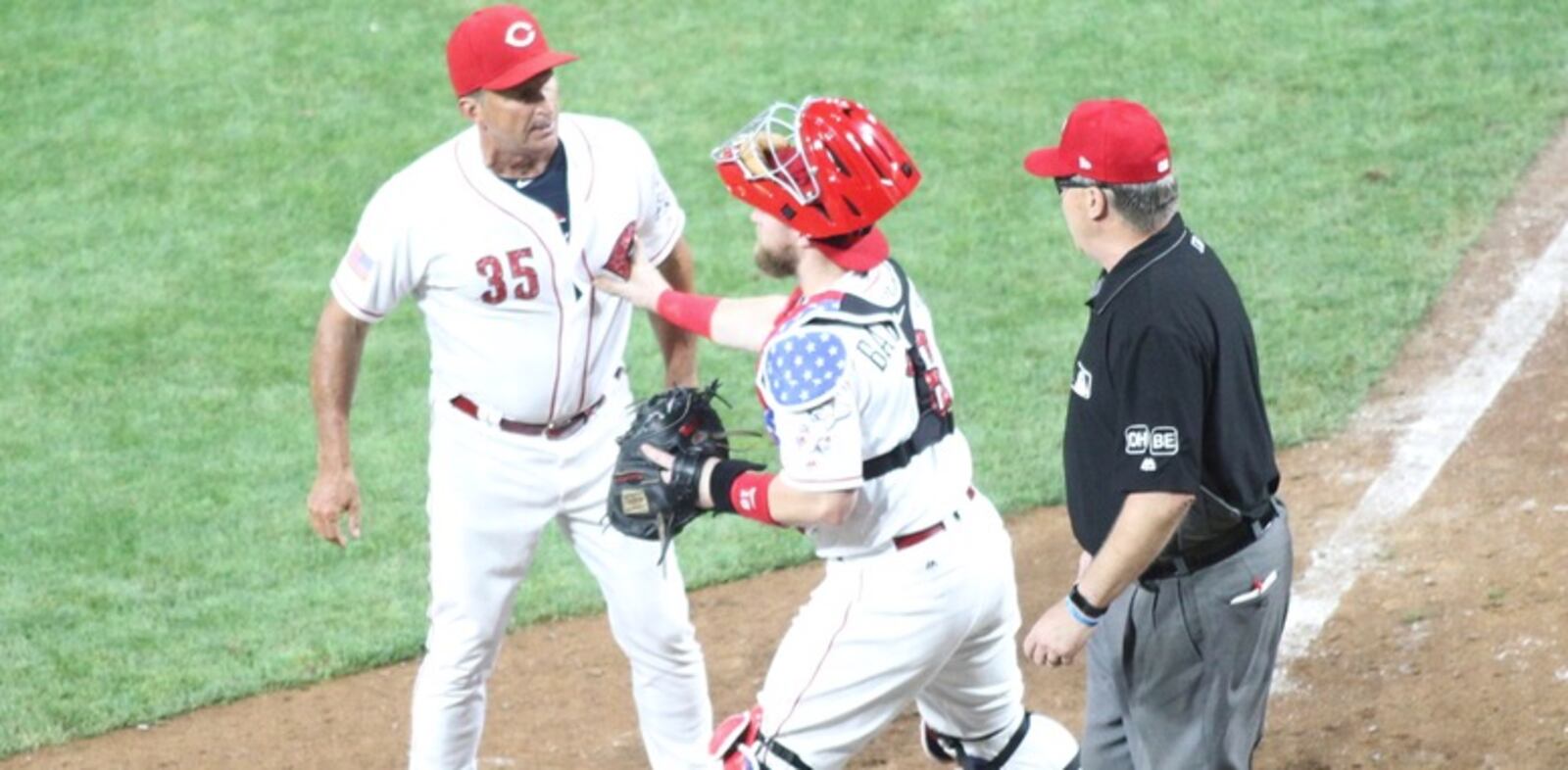 Reds catcher Tucker Barnhart holds back interim manager Jim Riggleman as he argues with Eric Cooper in the 12th inning of a game against the Chicago White Sox on Tuesday, July 3, 2018, at Great American Ball Park in Cincinnati. David Jablonski/Staff