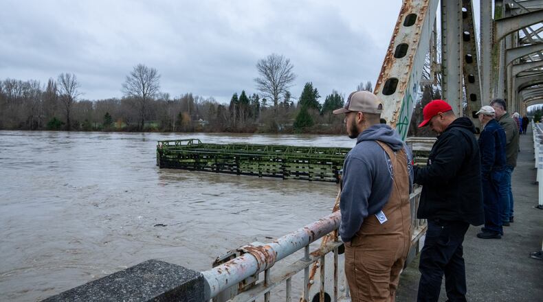 People stand on a bridge over the Skagit River in Lyman, Wash., Thursday, Dec. 11, 2025. (AP Photo/Stephen Brashear)