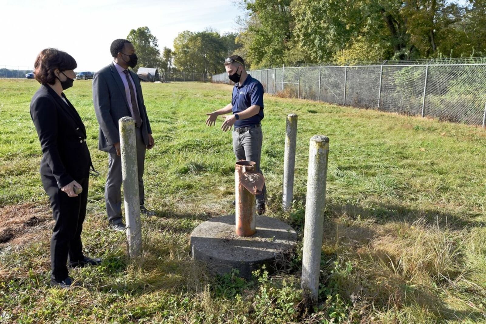 In this 2020 photo, Treva Bashore, restoration program manager, 88th Air Base Wing Civil Engineer Center (left), Amir Mott, deputy director, 88th Civil Engineer Group (center), and Dan Casey, lead field operations engineer, discuss a monitoring well at the fire training area of Wright-Patterson Air Force Base. (U.S. Air Force photo by Ty Greenlees)