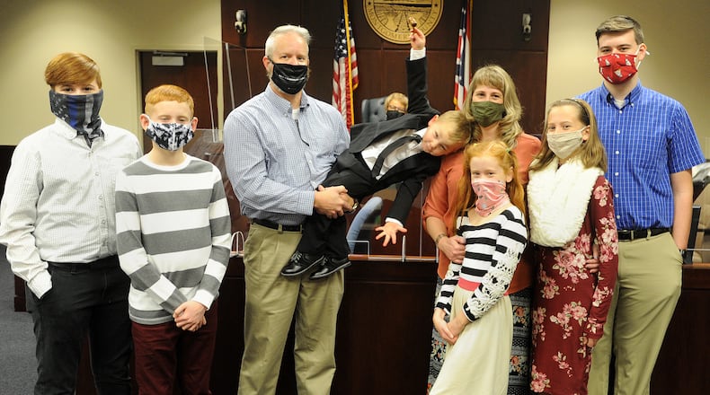 The Adkins family of Tipp City added a new family member during National Adoption Day proceedings in Montgomery County Probate Court Friday, November 20, 2020. Pictured from left to right, Isaiah, 17, Silas,12, father Randy, Judge Alice O. McCollum, Warren, 3, mother Priscilla, Lydia, 9, Sarah, 14 and Nathaniel, 19. MARSHALL GORBY\STAFF
