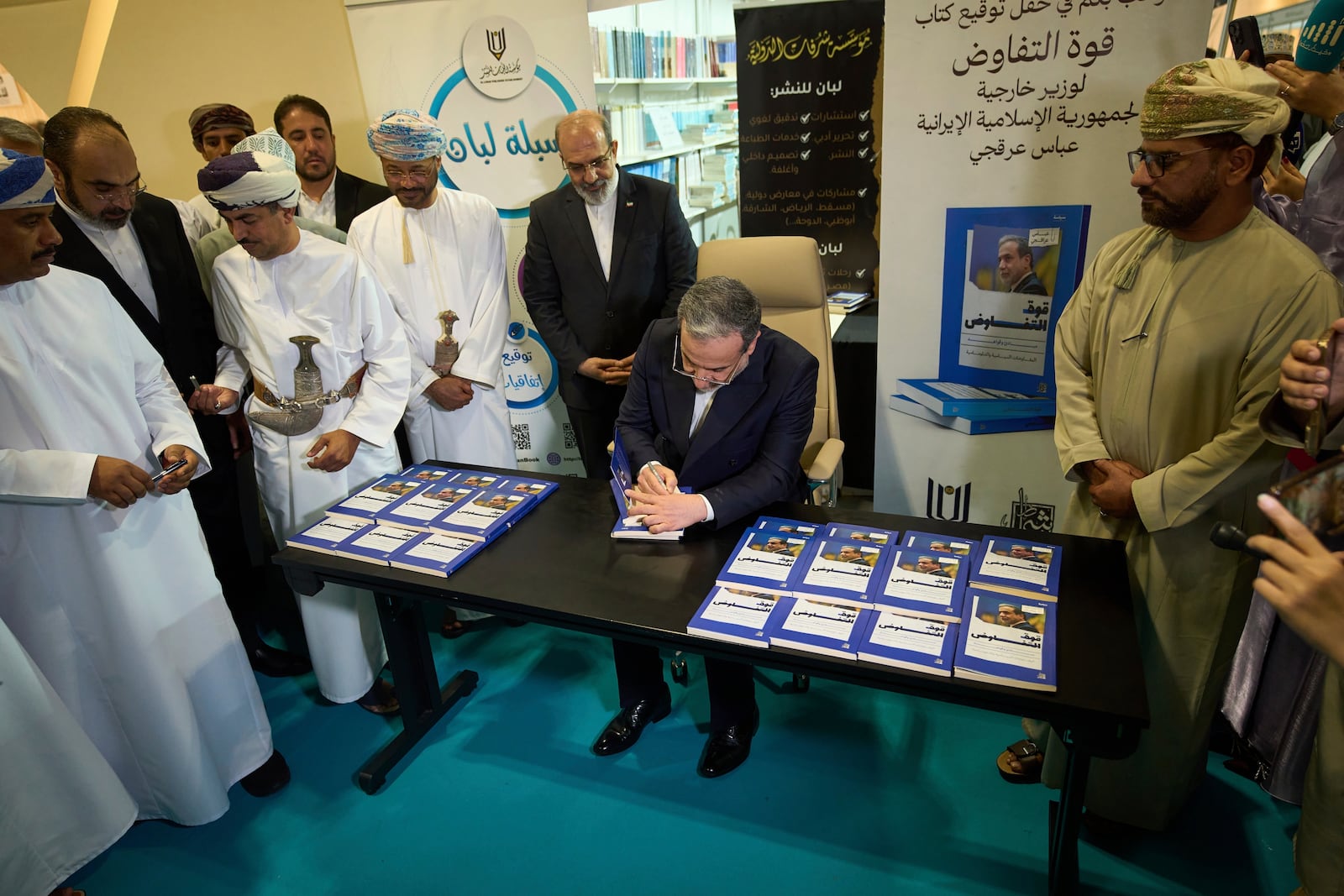 Iranian Foreign Minister Abbas Araghchi, signs copies of his book "The Power of Negotiation" at the Muscat International Book Fair in Oman, Friday, April 25, 2025. (AP Photo/ Fatima Shbair)