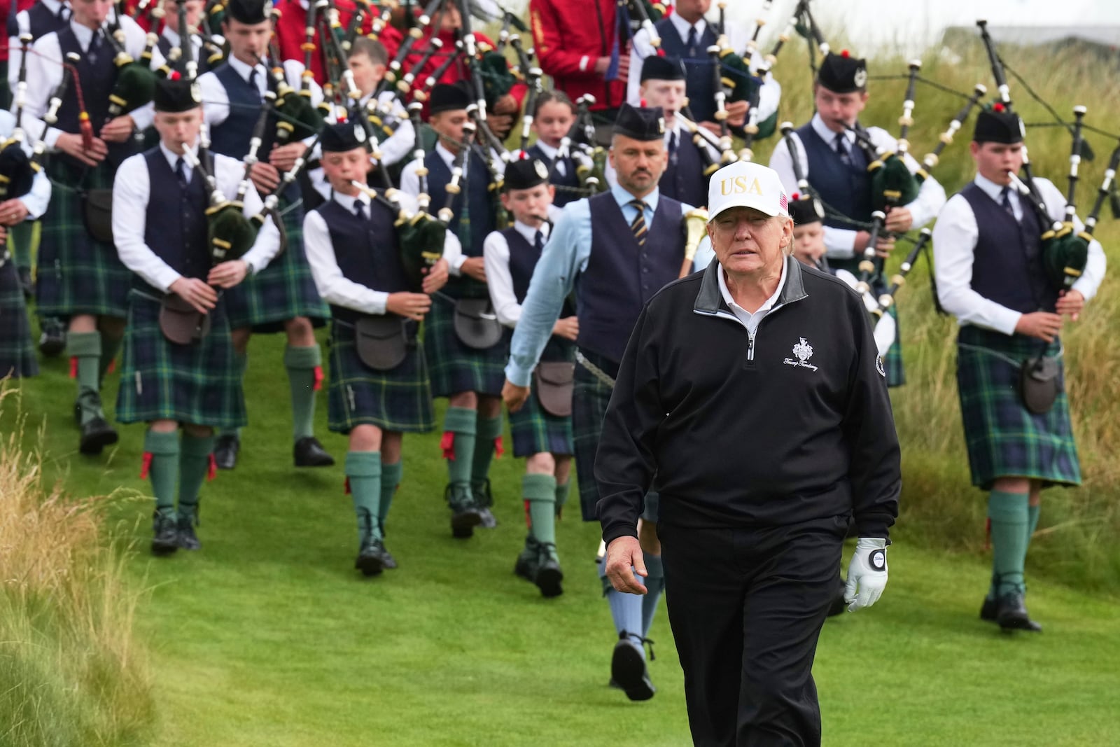 President Donald Trump arrives, followed by a bagpiper band, at the opening ceremony for the Trump International Golf Links golf course, near Aberdeen, Scotland, Tuesday, July 29, 2025. (AP Photo/Jacquelyn Martin)