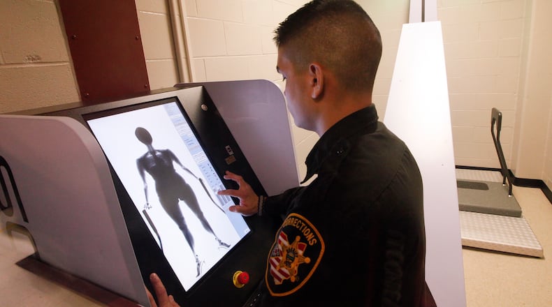 Tyler Viernes, a corrections officer at the Montgomery County Jail, demonstrates a new body scanning system that more than 25,000 inmates a year will pass through. CHRIS STEWART / STAFF
