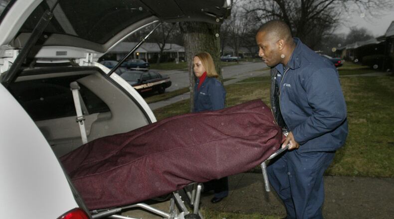 Brian Higgins, owner of GSSP Enterprise, Inc. and Ledra Boyd, in background, remove the body of a Miamisburg man who was discovered dead in his home by neighbors on Friday. Staff photo by Chris Stewart