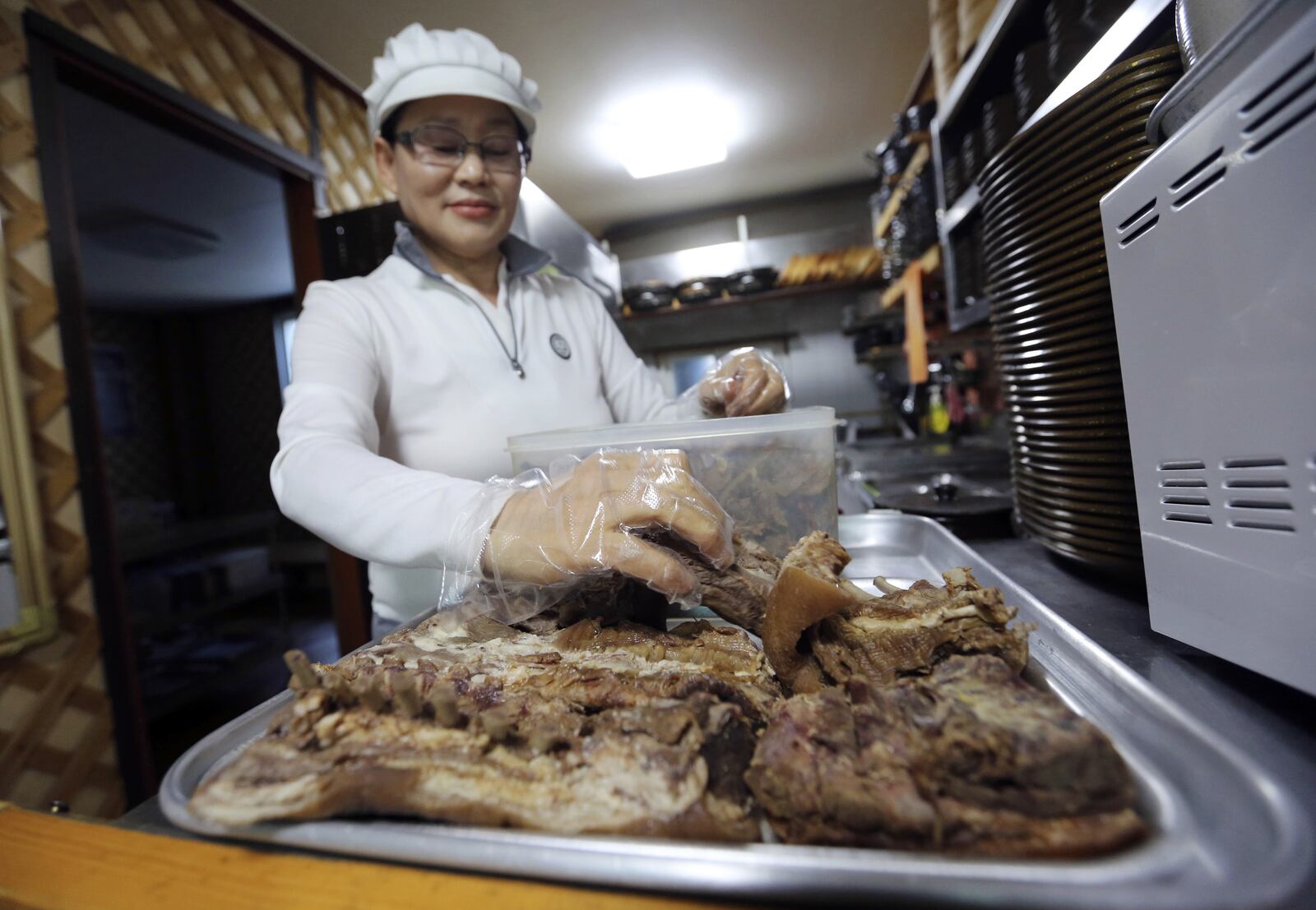 In this Dec. 12, 2017, photo, Park Young-ae, 60, owner of Young Hoon Restaurant, arranges dog meats at her restaurant in Pyeongchang, South Korea. Just weeks before the Olympics, a culture clash is taking place in Pyeongchang, and it's only partly about the anticipatory jitters before a swarm of foreigners arrives. There's a strain of unease as the government, desperate to measure up to an Olympic host city image, pushes for change in an indebted, aging backwater that relies on tourism and fisheries with no real industrial base. Park said "I have been selling dog meat for decades. It is really difficult for me to change my menu just because of the Olympics." (AP Photo/Ahn Young-joon)
