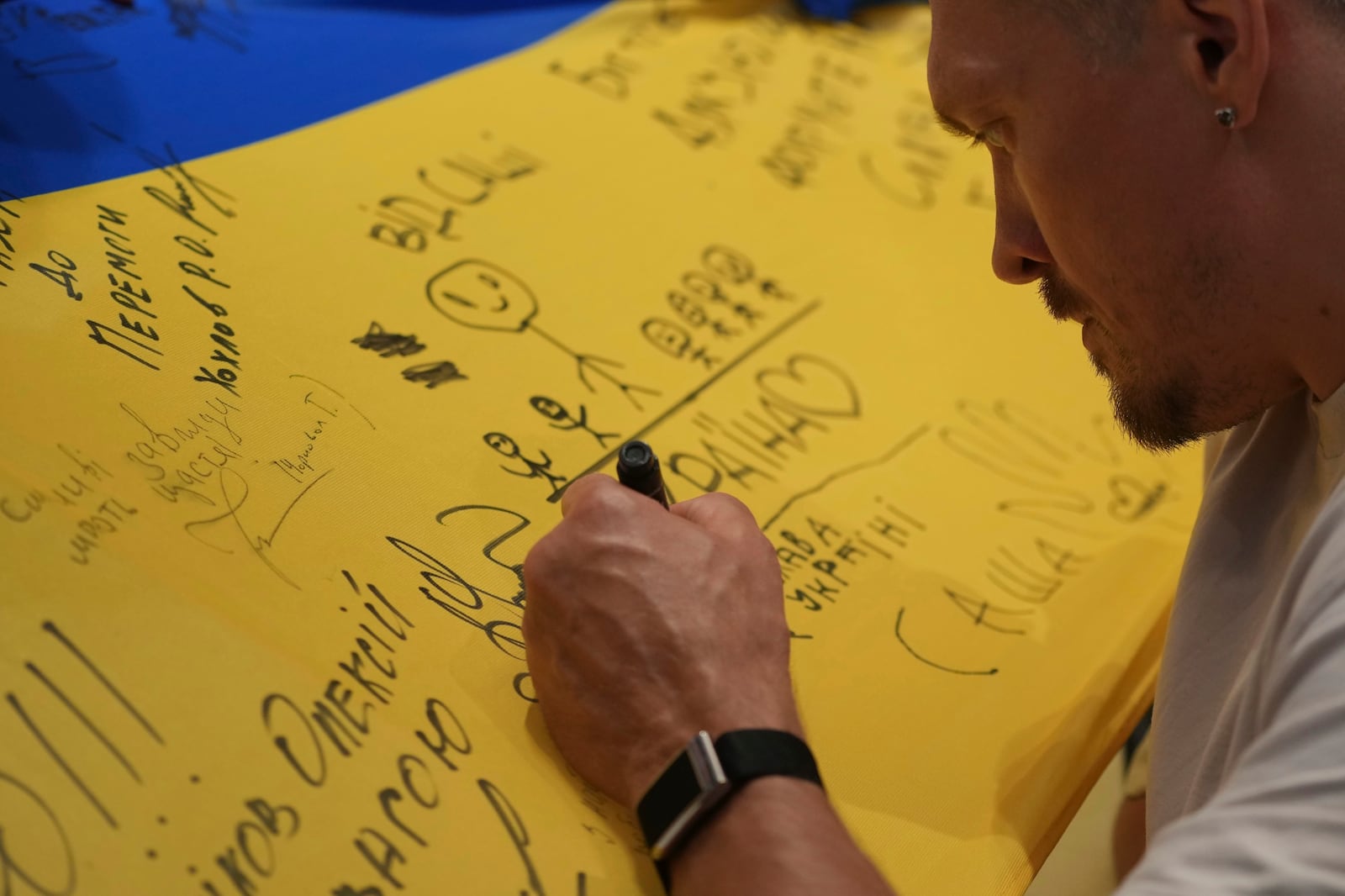 Ukraine's boxer Oleksandr Usyk signs autograph as he meets the Ukrainian war veterans, who are employees of Ukrainian power company DTEK at a hotel in Battersea Park in London, Thursday, July 17, 2025 ahead of the undisputed heavyweight champion boxing fight between Britain's Daniel Dubois and Oleksandr Usyk on Saturday. (AP Photo/Kin Cheung)