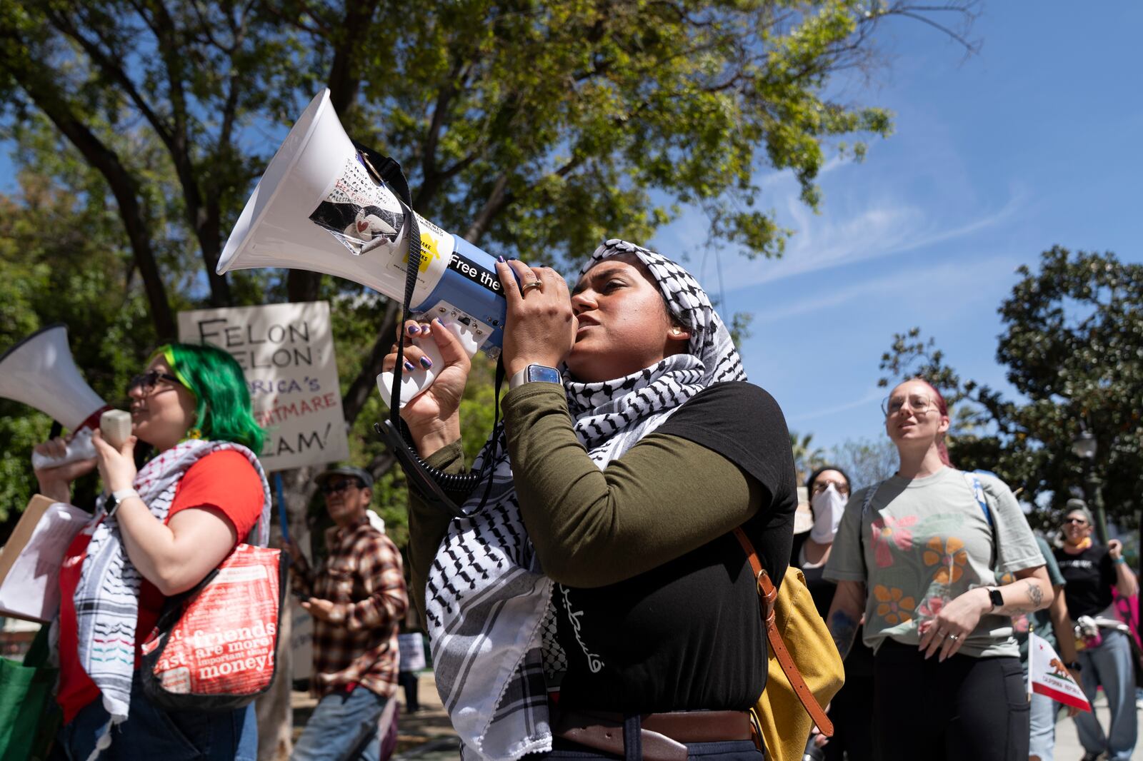 Michelle Parvool chants into a megaphone at a rally against President Donald Trump and Tesla CEO Elon Musk in San Jose, Calif., on Saturday, April 5, 2025, as part of the nationwide "Hands Off!" protest. (AP Photo/Emily Steinberger)