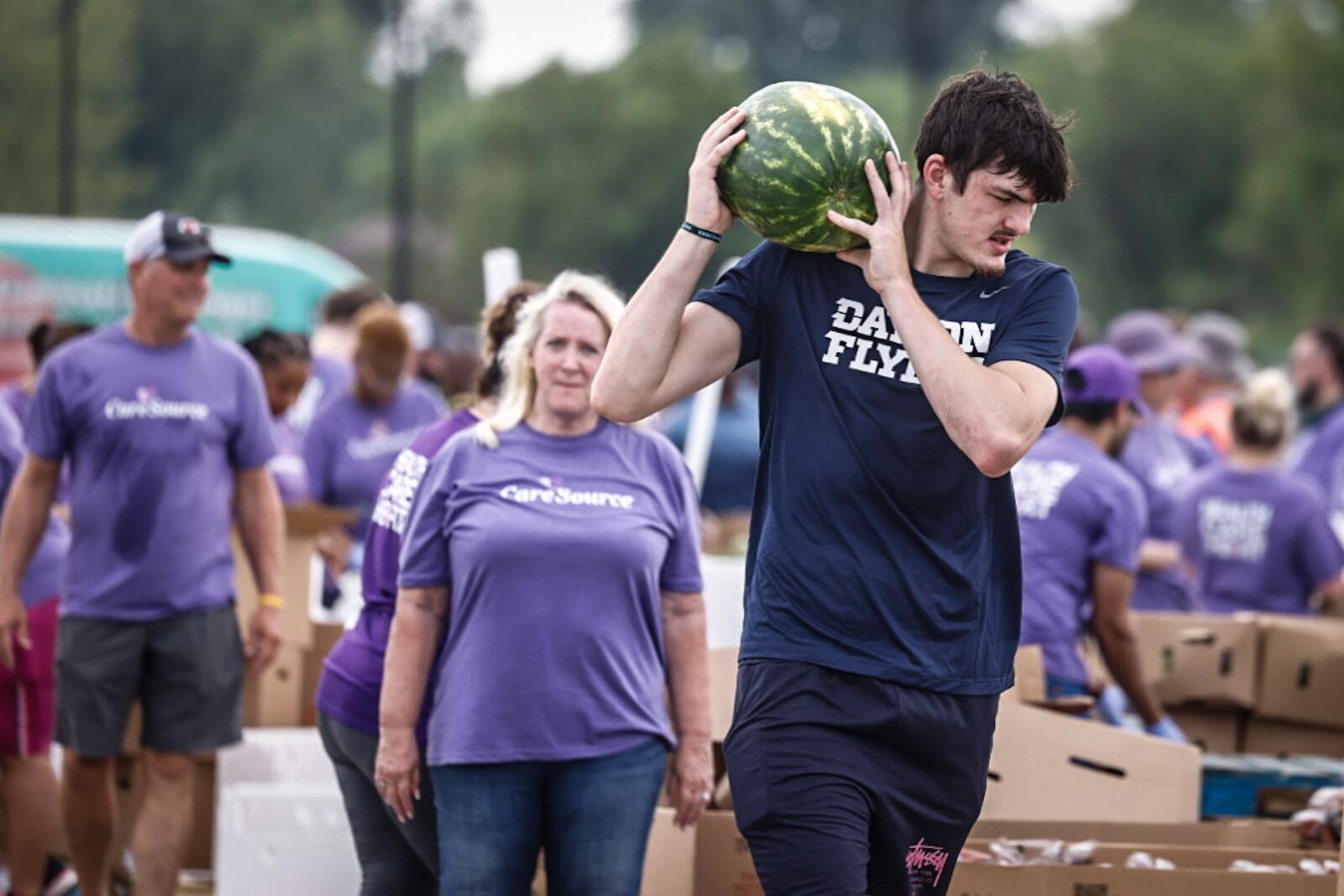 Dayton Flyer forward Isaac Jack along with other team members help the Foodbank and CareSource with a mini food distribution at the Montgomery County Fairgrounds Thursday 20, 2024. JIM NOELKER/STAFF