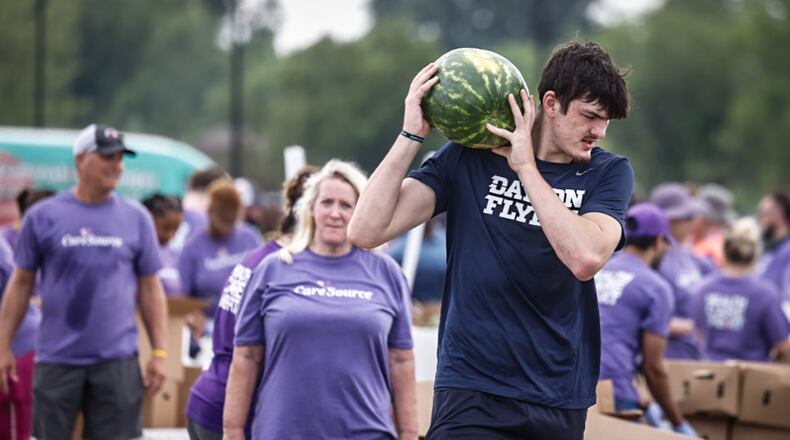 Dayton Flyer forward Isaac Jack along with other team members help the Foodbank and CareSource with a mini food distribution at the Montgomery County Fairgrounds Thursday 20, 2024. JIM NOELKER/STAFF