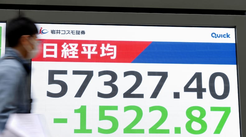 People walk in front of an electronic stock board showing Japan's Nikkei index at a securities firm Monday, March 1, 2026, in Tokyo.(Yohei Fukai/Kyodo News via AP)