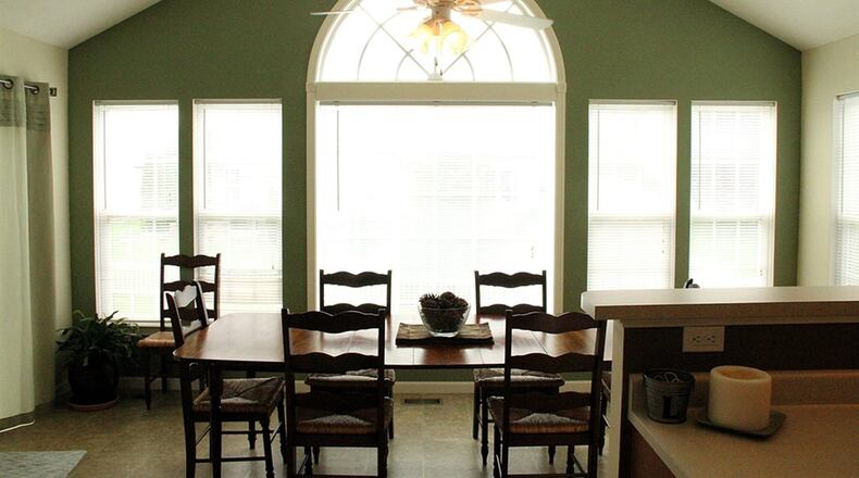 In the bright morning room a paddle fan centers the vaulted ceiling. A row of tall windows flank the extra-wide arched window at the center of the far wall.