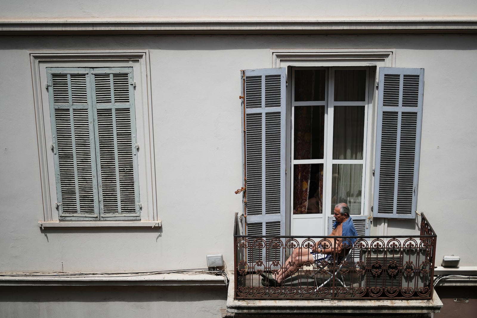 A man sits on the balcony during a electricity outage in Cannes, southern France, Saturday, May 24, 2025. (AP Photo/Natacha Pisarenko)