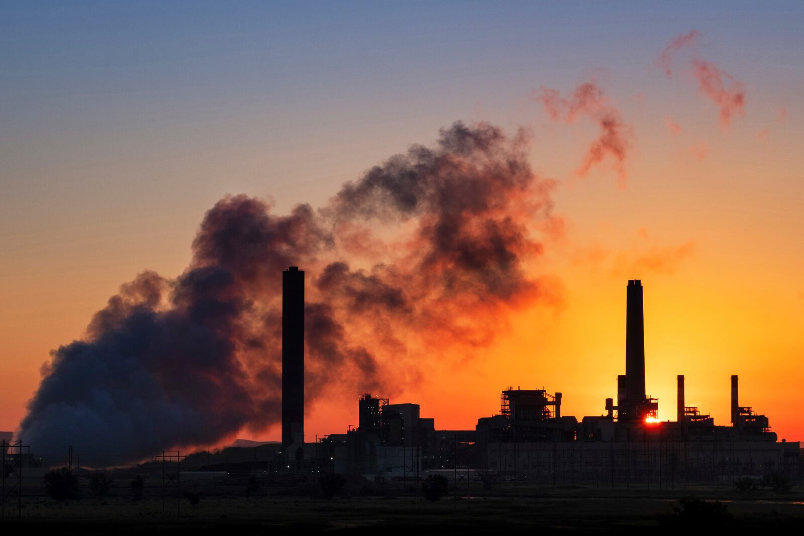 FILE - The Dave Johnson coal-fired power plant is silhouetted against the morning sun in Glenrock, Wyo., July 27, 2018 (AP Photo/J. David Ake, File)