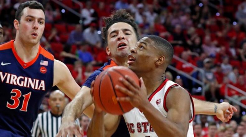 Virginia's London Perrantes, center, defends North Carolina State 's Dennis Smith Jr., right, with Jarred Reuter, left, nearby during the first half of an NCAA college basketball game in Raleigh, N.C., Saturday, Feb. 25, 2017. (AP Photo/Karl B DeBlaker)