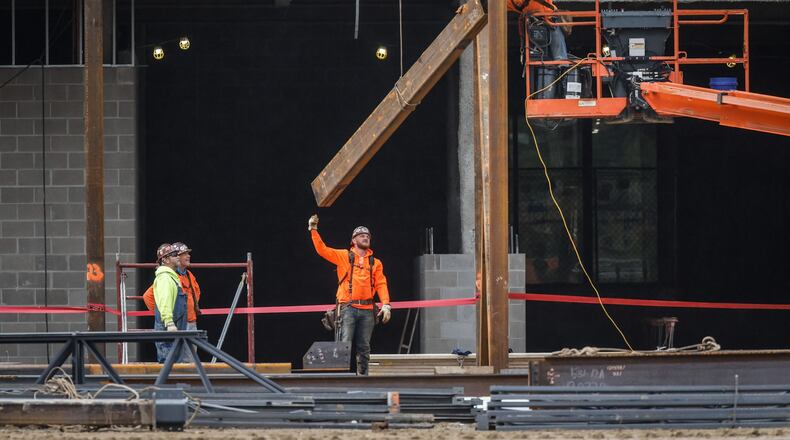 Workers hoist steel on the remodel and expansion of the Miami Valley Career Tech Center at 6800 Hoke Rd. JIM NOELKER/STAFF