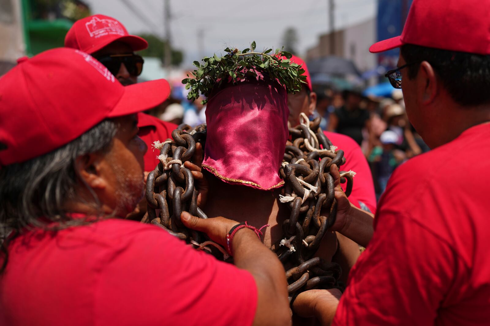 A masked penitent is helped with the chains he bears during a Holy Week procession in Atlixco, Mexico, on Good Friday, April 18, 2025. (AP Photo/Eduardo Verdugo)