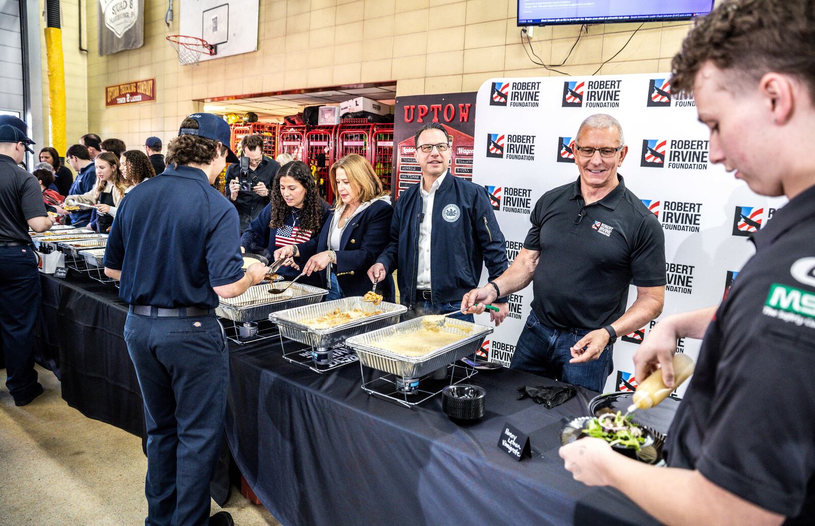 Pennsylvania Gov. Josh Shapiro, joined by first lady Lori Shapiro and chef Robert Irvine, at right, serve lunch to firefighters to thank them for responding to Sunday's arson attack at the Governor's Residence, Thursday, April 17, 2025. (Dan Gleiter/The Patriot-News via AP)