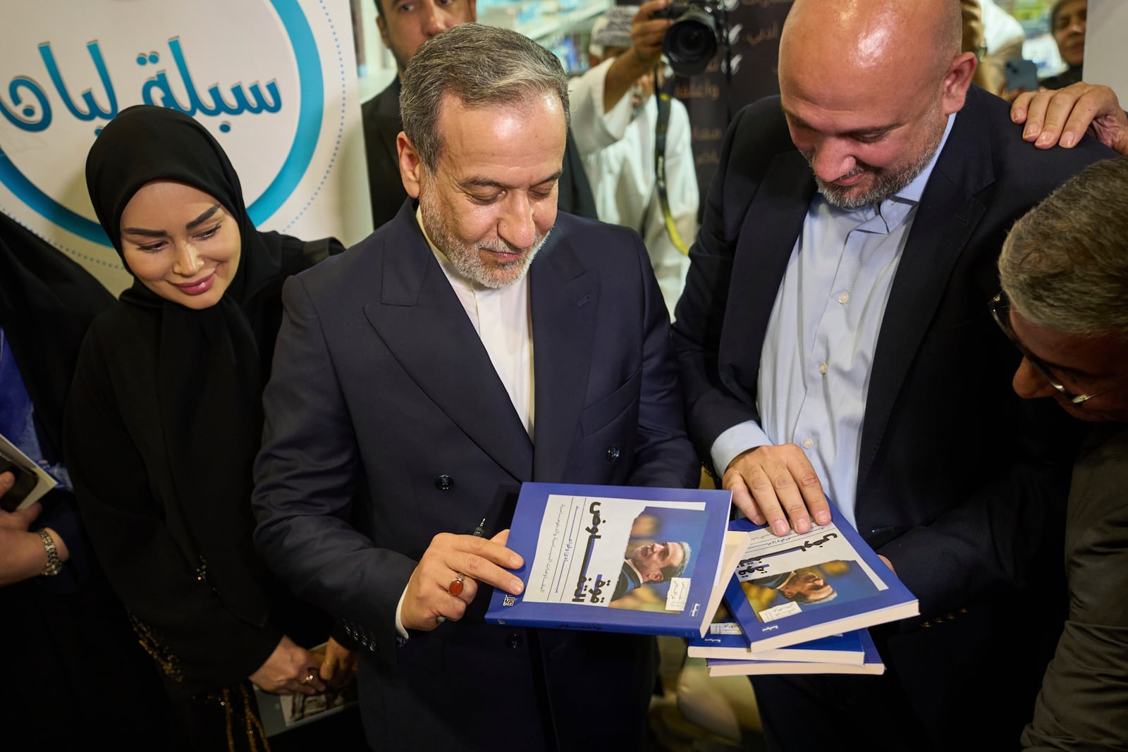 Iranian Foreign Minister Abbas Araghchi, holds up his book "The Power of Negotiation" at the Muscat International Book Fair in Oman, Friday, April 25, 2025. (AP Photo/ Fatima Shbair)