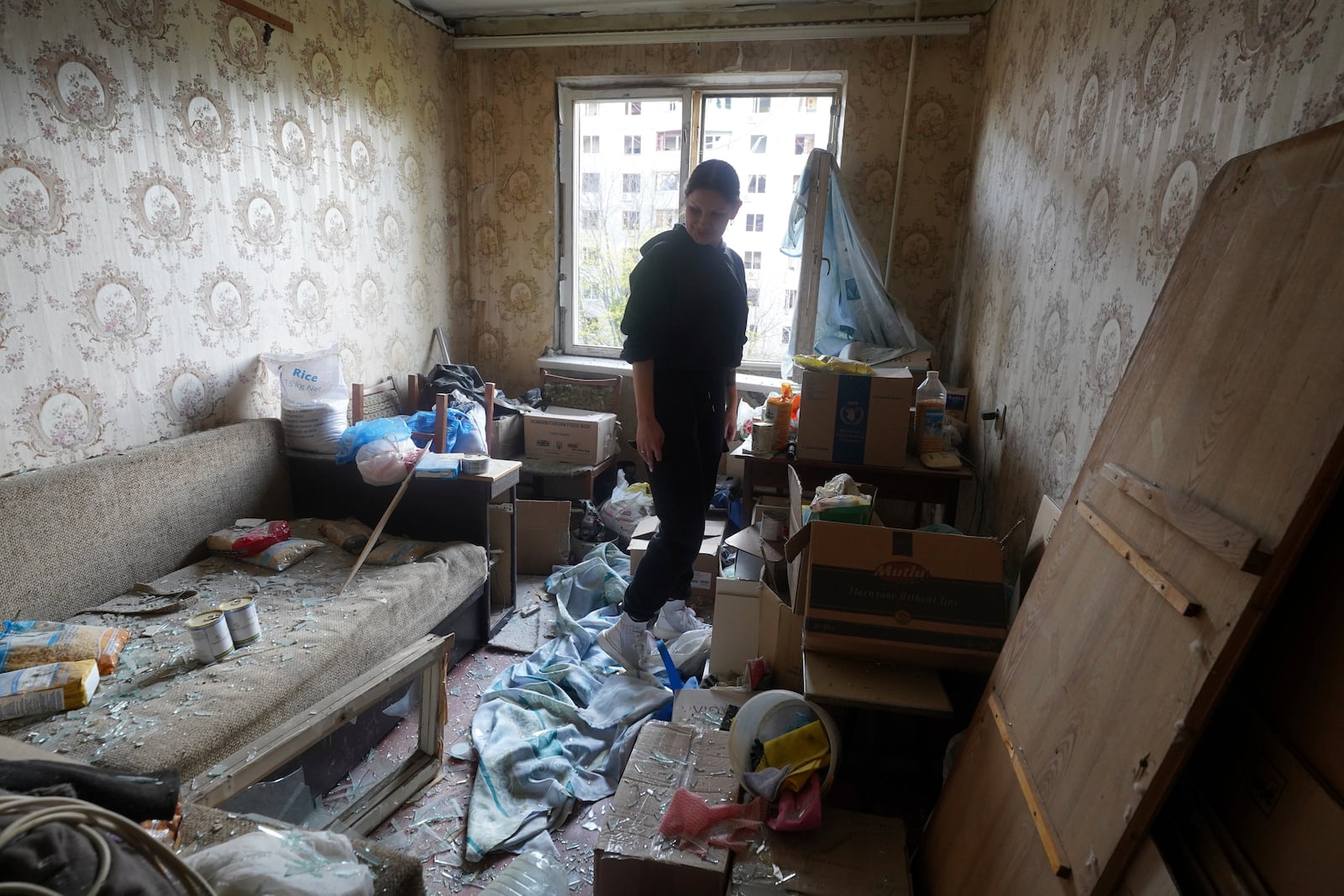 A woman stands inside her apartment damaged by a Russian strike in Kharkiv, Ukraine, Friday April 18, 2025. (AP Photo/Andrii Marienko)