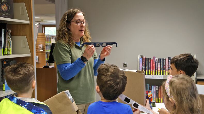 Penny Dunbar, from National Trail Parks and Recreation District, explains to a group of children how important it is to wear eclipse glasses Wednesday, April 3, 2024 during a program called Solar Shadow at the New Carlisle Public Library. BILL LACKEY/STAFF