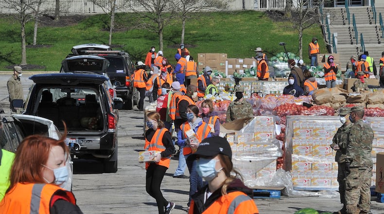 Volunteers and members of the National Guard load food into vehicles at Wright State’s Nutter Center on Tuesday morning. The Foodbank was distributing food to Greene County residents. MARSHALL GORBY/STAFF