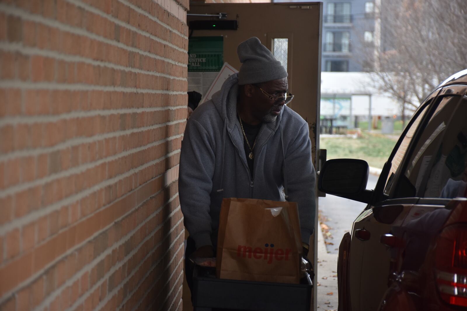 Tracy Davis Sr., 67, of Dayton, brings food out to a vehicle outside of Good Neighbor House on Wednesday, Dec. 4, 2024. CORNELIUS FROLIK / STAFF