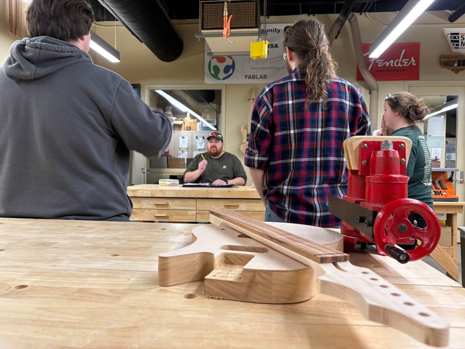 Students gather around Sinclair Community College instructor Matt Mongin to learn the secrets of creating electric guitars. THOMAS GNAU/STAFF