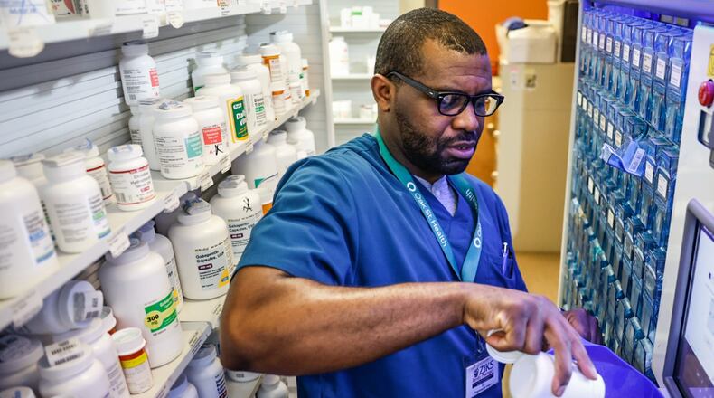 Ziks Family Pharmacy pharmacist intern, Emmanuel Ukattah Jr. fills a robot that disseminates prescriptions at the store on West Third Street on June 12, 2023. JIM NOELKER/STAFF