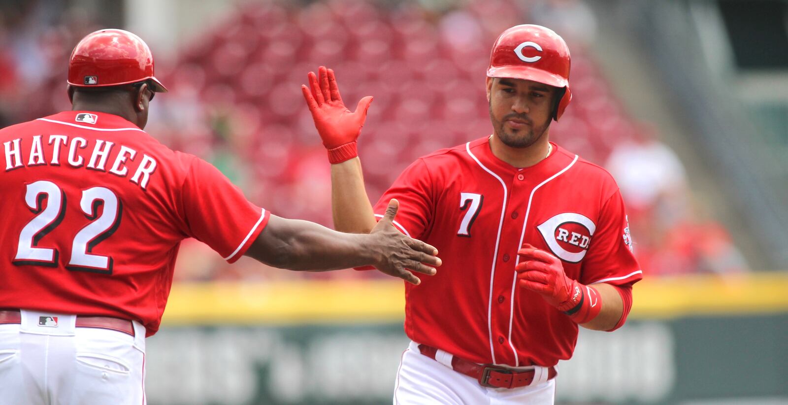 The Reds’ Eugenio Suarez slaps hands with third-base coach Billy Hatcher after a home run against the Nationals on Monday, July 17, 2017, at Great American Ball Park in Cincinnati. David Jablonski/Staff