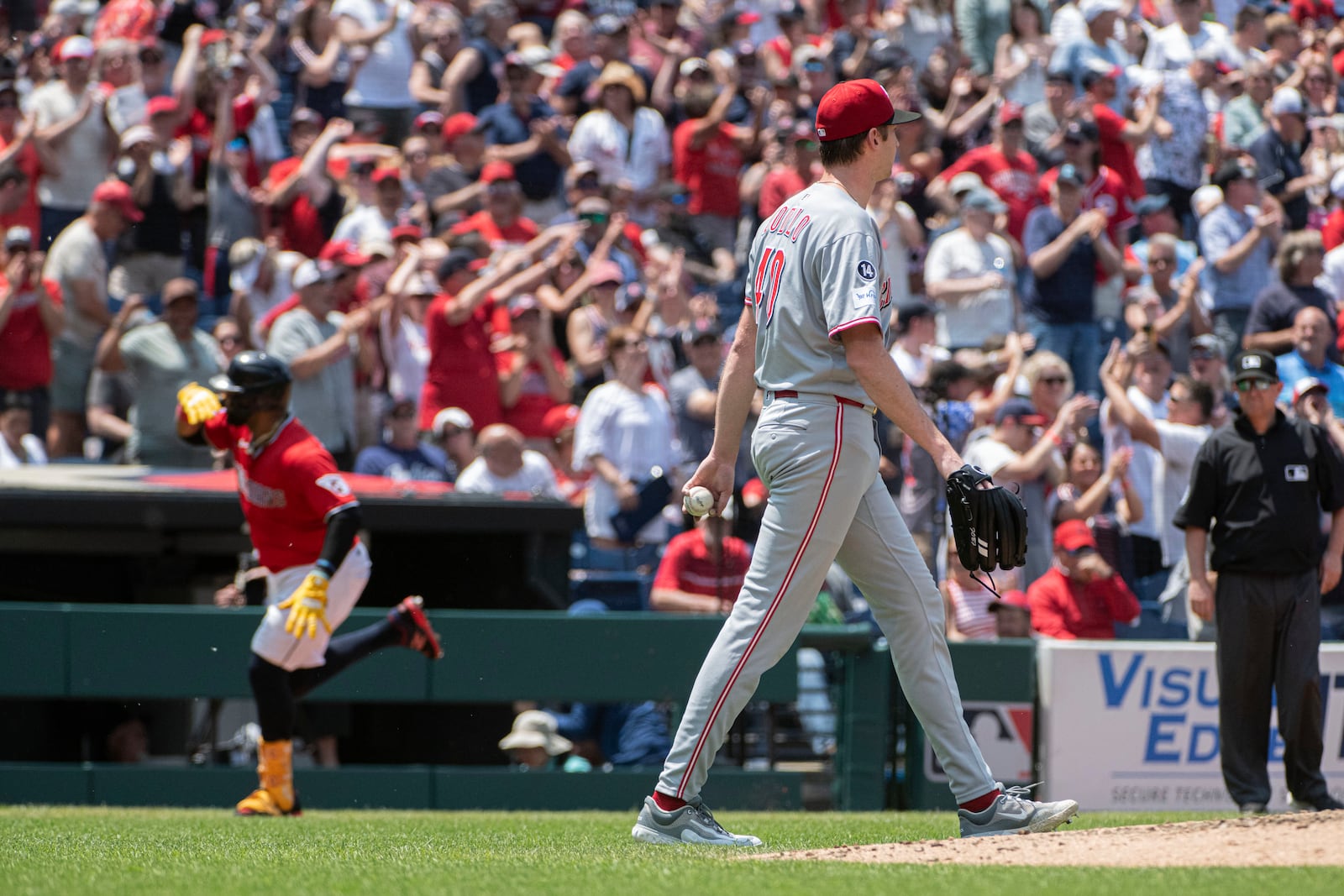 Cincinnati Reds starting pitcher Nick Lodolo, front, walks back to the mound as Cleveland Guardians' Carlos Santana, rear, rounds the bases after hitting a three-run home run during the third inning of a baseball game, Wednesday, June 11, 2025, in Cleveland. (AP Photo/Phil Long)
