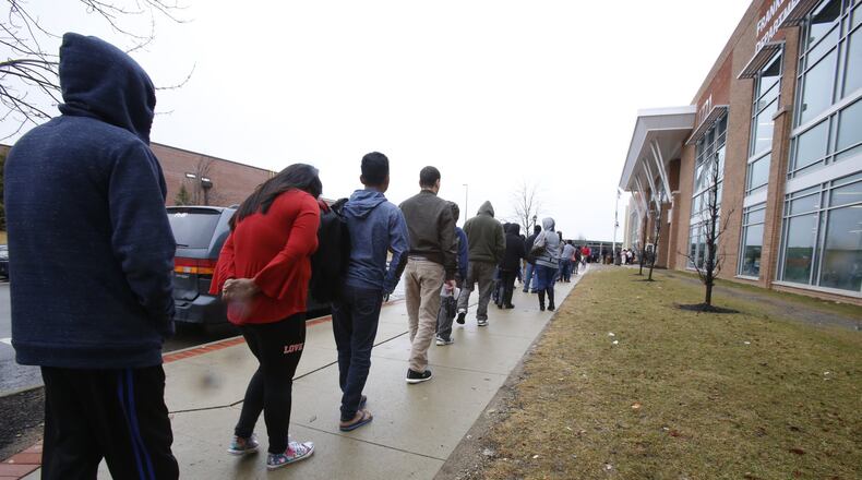 Members of a recently arrived family of refugees from Bhutan wait in a long line outside the Franklin County Department of Job and Family Services in Columbus, Ohio, on Wednesday, Feb. 21, 2018. The family can apply for various forms of government assistance, though their goal is to find work quickly. (AP Photo/Martha Irvine)