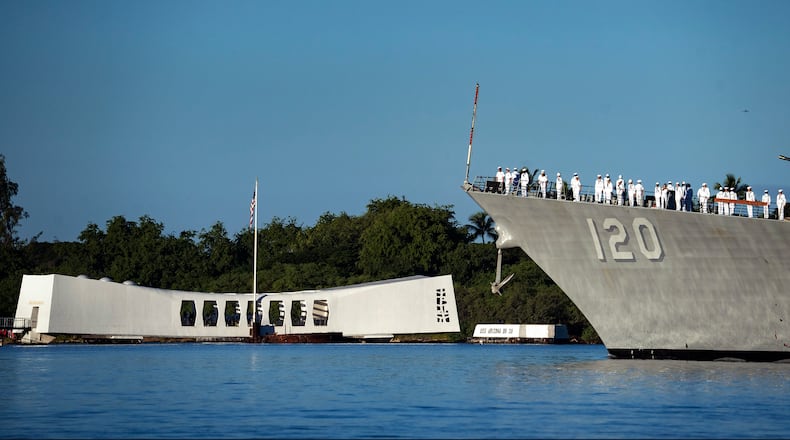 Sailors aboard the USS Carl M. Levin render honors while passing the USS Arizona Memorial and the sunken battleship the USS Arizona during the 83rd Pearl Harbor Remembrance Day ceremony, Saturday, Dec. 7, 2024, in Honolulu. (AP Photo/Mengshin Lin)
