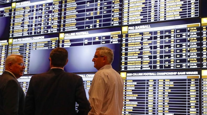 Indiana Gov. Eric Holcomb (right) talks with Ron Baumann (center), general manager of Indiana Grand Racing & Casino, and Shelbyville Mayor Tom Debaun in the sports betting area at the Indiana Grand Racing & Casino in Shelbyville, Ind., on Sept. 1, 2019. Holcomb placed the first sports bets after sports betting became legal in Indiana. Ohio is behind its neighbors in legalizing sports betting. Michael Conroy / ASSOCIATED PRESS
